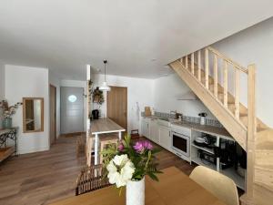 a kitchen and a living room with a staircase at Villa Petit Caprice - Piscine privée au calme dans jardin arboré in Lanton