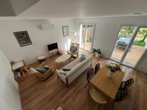 a living room with a couch and a table at Villa Petit Caprice - Piscine privée au calme dans jardin arboré in Lanton