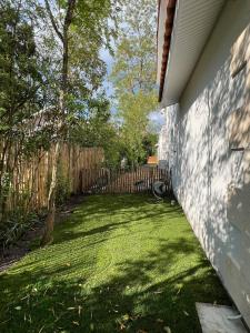 a backyard with a fence and a grass yard at Villa Petit Caprice - Piscine privée au calme dans jardin arboré in Lanton