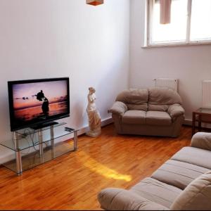uma sala de estar com uma televisão de ecrã plano e um sofá em Apart Lwowska em Varsóvia