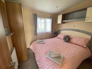 una camera da letto con un letto rosa e asciugamani di Sundowner Holidays a Sandown