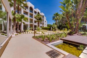 a building with a courtyard with a pond and palm trees at Falésia Hotel - Adults Only in Albufeira