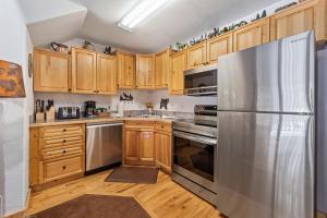 a kitchen with wooden cabinets and a stainless steel refrigerator at Bugle Pointe A10 by Estes Park Condos in Estes Park