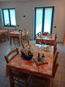een eetkamer met tafels, stoelen en ramen bij Suite Onorio B&B Zia Vivina in Sorico