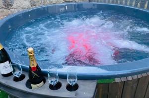 Un jacuzzi con dos botellas de vino y copas de vino. en Vila Themis, en Călimăneşti