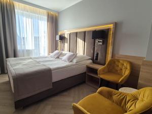 a bedroom with a large bed and a chair at Tramontana Family & Wellness in Darłówko