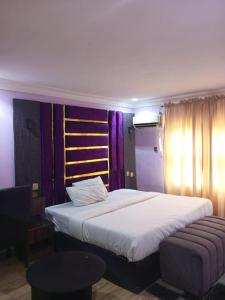 a bedroom with a large white bed and a chair at Dino international Hotel in Ibadan