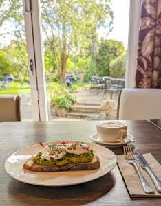 un sándwich en un plato en una mesa con una taza de café en The Mallard Hotel, en Gullane