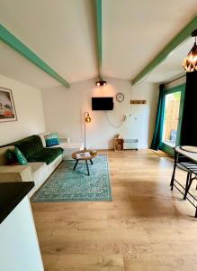 a living room with a couch and a tv at Cozy Ibiza style beach house with jacuzzi & private garden near Amsterdam in Vijfhuizen