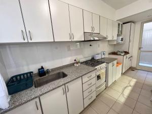 una cocina con armarios blancos y fregadero en Mendoza C&D en Godoy Cruz