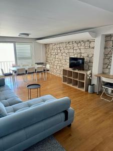 a living room with a blue couch and a stone wall at Villa Rozika in Baška Voda