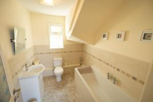 Sea Villa Cottage في تاربيرت: حمام مع حوض ومرحاض وحوض استحمام