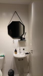 a bathroom with a sink and a tv on the wall at Studio 1908: A sua casa de aluguel in São Paulo