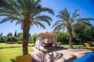 een tuinhuisje in een tuin met 2 palmbomen bij Villa 'Cartier' in Marrakesh