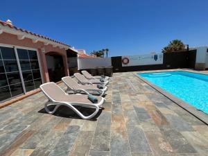 a row of lounge chairs next to a swimming pool at Villa Nodrog in Costa de Antigua