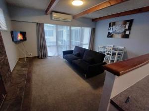 a living room with a black couch and a table at Aqua Apartment in Napier