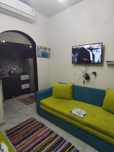 BTM RENTAL CHALETS PORTO MATROUH FAMiLY ONLY في مرسى مطروح: غرفة معيشة مع أريكة وتلفزيون على الحائط
