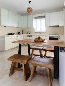 a kitchen with a wooden table with benches and a bowl of fruit at Vasilopoulos Residences - Villa Kalliste in Argostoli