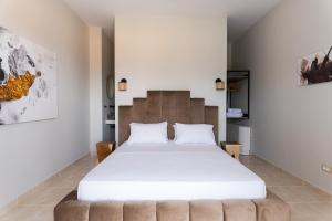 a bedroom with a large white bed with a brown headboard at Vasilopoulos Residences - Villa Kalliste in Argostoli +28 photos