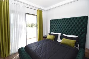 um quarto com uma cama grande e uma cabeceira verde em Mamica Luxury Villa em Laganas