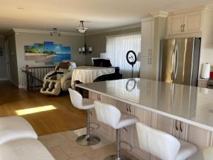 a kitchen with a counter with white chairs and a living room at View of Ocean & MOUNT BAKER in White Rock