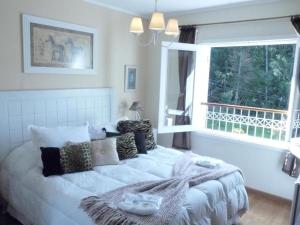- un lit blanc dans une chambre avec fenêtre dans l'établissement Pousada Atalaia Premium, à Campos do Jordão