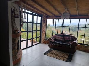 uma sala de estar com um sofá de couro num quarto com janelas em cabaña la esmeralda em El Peñol