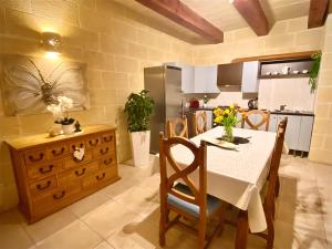 a kitchen with a white table and chairs and a kitchen with a kitchen at Farmhouse Grazzja with pool in Qala
