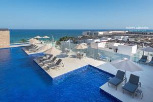 a swimming pool with chairs and umbrellas and the ocean at Trendy 1 BR apartment in Cruz Con Mar Brand New Building in Playa del Carmen