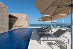 a swimming pool with lounge chairs and umbrellas at Trendy 1 BR apartment in Cruz Con Mar Brand New Building in Playa del Carmen