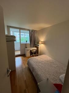 a bedroom with a bed and a desk and a window at Chambre proche Stade de France in Saint-Denis