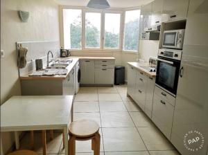 a kitchen with white appliances and a table with a stool at Chambre proche Stade de France in Saint-Denis