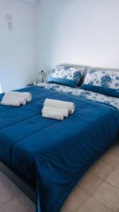a blue bed with blue sheets and white pillows at Attico una finestra sulle Isole Eolie in Brolo