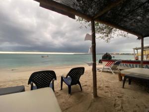 una mesa y sillas en una playa con el océano en Posada Shekinah Barú en Playa Blanca