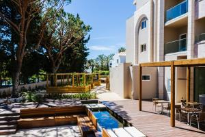 a patio with a pool and a wooden deck at Falésia Hotel - Adults Only in Albufeira