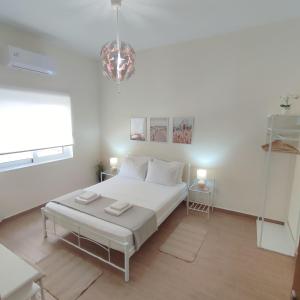 biała sypialnia z łóżkiem i żyrandolem w obiekcie Preveza Mosaic House w Prewezie