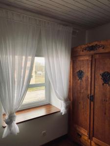 ventana con cortinas blancas y armario de madera en Antique suburban apartment, en Türi