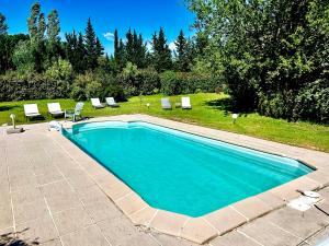 una piscina con sillas y un patio con árboles en Domaine Plan des Devens, en Roussillon