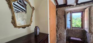 einen Spiegel und eine Vase auf einem Tisch in einem Zimmer in der Unterkunft Casa do Moleiro in Cinfães
