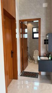 ein Badezimmer mit einem WC und einer Holztür in der Unterkunft كوخ القرية أبها 2 in Abha