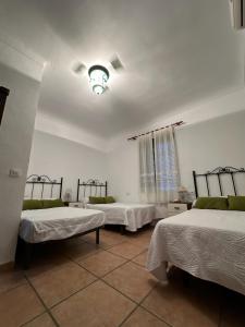 a room with three beds and a chandelier at Dehesa Elías in Lucena