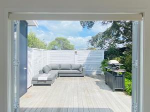 a patio with a couch and a grill at Surfdale Serenity - Bed & Breakfast in Oneroa