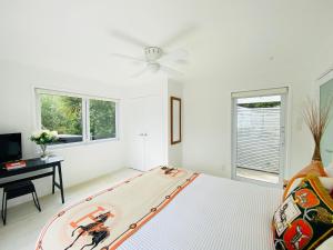 a white room with a bed and a ceiling fan at Surfdale Serenity - Bed & Breakfast in Oneroa