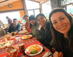 eine Gruppe von Menschen, die an einem Tisch mit Essen sitzen in der Unterkunft Weninger Lodge in Urubamba