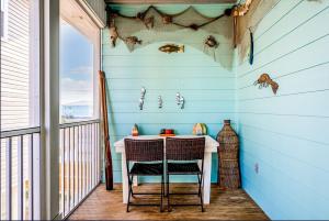 Habitación con balcón con mesa y 2 sillas. en Crawling Distance Beach House, en Pensacola