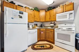 a kitchen with white appliances and wooden cabinets at Bugle Pointe A01 by Estes Park Condos in Estes Park