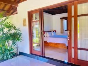 a bedroom with a bed and sliding glass doors at Umah Teresna in Ubud