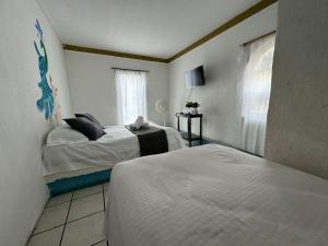 a bedroom with two beds and a window at Hotel El Mexicano Tepic Centro in Tepic