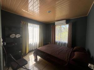 1 dormitorio con 1 cama y 2 ventanas. en Casa Ara Macao, en Paquera