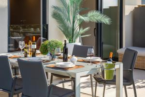 a white table with chairs and wine bottles on it at Enjoyer - Seafront apartment with PRIVATE Heated POOL and terrace in Split